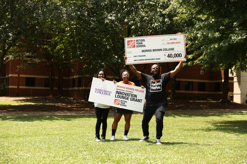 Group of people standing in a grassy area holding RYS grant checks